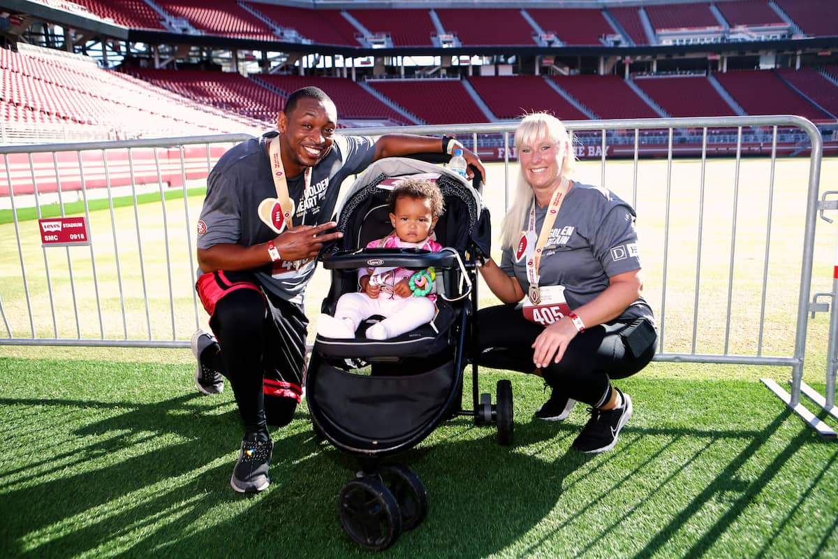 Two race participants pose with a baby in a stroller.