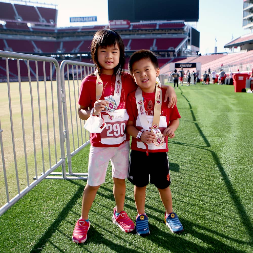 Two young siblings hold their race medals up for the camera.